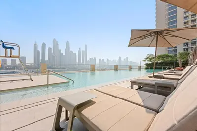 a pool with chairs and an umbrella on a building at Silkhaus Partial Marina View 1BDR in Marina Vista in Dubai