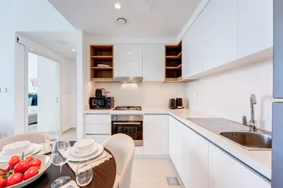 a kitchen with white cabinets and a table with a bowl of fruit at Silkhaus High Floor 1 BDR In The Heart of Downtown in Dubai