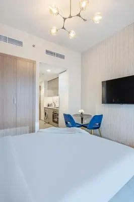 a room with two blue chairs and a television at Lux-Furnished Stu Couple-Friendly Near Downtown in Dubai