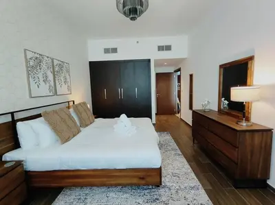 a bedroom with a large bed and a dresser at 1 Bed room - Azizi Daisy - Furjan in Dubai