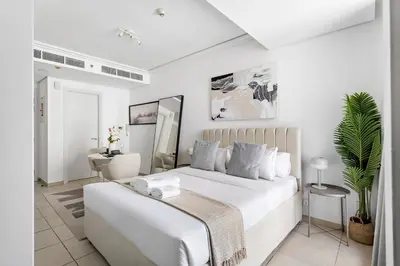 a white bedroom with a large bed and a desk at Stonetree - Goldcrest Views 2 - Prime Location in Dubai
