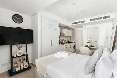 a white bedroom with a large bed and a kitchen at Stonetree - Goldcrest Views 2 - Prime Location in Dubai