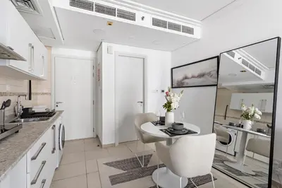 a kitchen with white cabinets and a table and chairs at Stonetree - Goldcrest Views 2 - Prime Location in Dubai