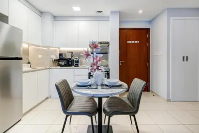 a kitchen with a table with chairs and a refrigerator at Trophy - Discover Tranquility Living in this Sleek Sanctuary in Dubai