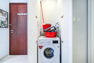 a washing machine with a bucket on top of it at Trophy - Discover Tranquility Living in this Sleek Sanctuary in Dubai