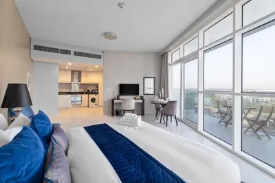 a bedroom with a large bed and a living room at Nasma Luxury Stays - Charming Studio at DAMAC Hills Artesia Tower C in Dubai