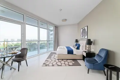 a bedroom with a bed and a table and chairs at Nasma Luxury Stays - Charming Studio at DAMAC Hills Artesia Tower C in Dubai