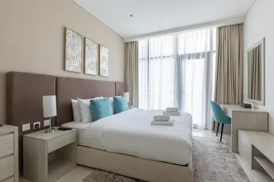 a bedroom with a large bed with blue pillows at Chic Palm Studio with Infinity Pool in Dubai