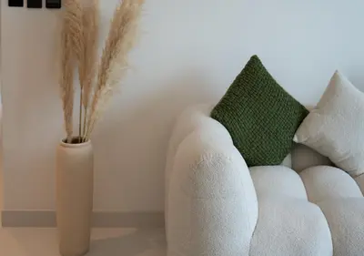 a white vase next to a white couch and a vase with feathers at Waterfront ,High Floor 2BED with Private Beach Access in Dubai