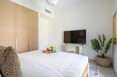 a bedroom with a white bed with a tv on the wall at Frank Porter - Bayshore at Creek Beach in Dubai