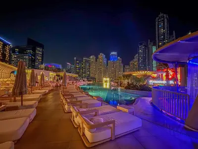 a rooftop bar with a pool and a city at night at Frank Porter - Emaar Residences Dubai Marina in Dubai