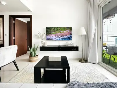 a living room with a black coffee table and a tv at Trophy - Springs Suite with Cozy Balcony Garden in Dubai