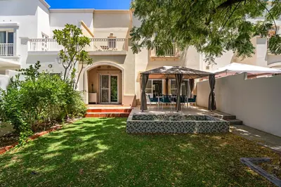 a house with a yard with chairs and an umbrella at Whole 3 BR with Maids Room House - The Springs - Privat Garden in Dubai