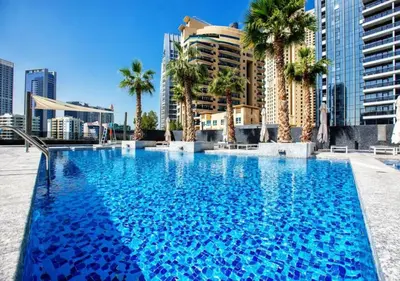 a large swimming pool with palm trees and buildings at Dubaiashome - Luxury Special Stay in Dubai