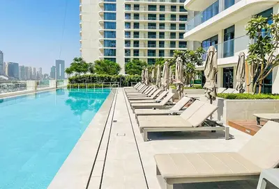 a pool with chairs and umbrellas on a building at Marina Vista 1BR Sea View Luxury Escape in Dubai