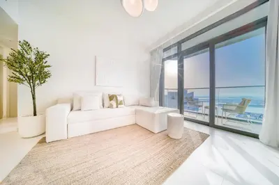 a living room with a white couch and a large window at Marina Vista 1BR Sea View Luxury Escape in Dubai