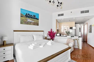 a white bedroom with a large bed and a couch at WelHome - Relaxing and Fancy Studio Apt with City View in Dubai