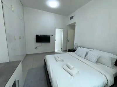 a white bedroom with a large bed with towels on it at Cozy 2 Bedroom Retreat in Dubai