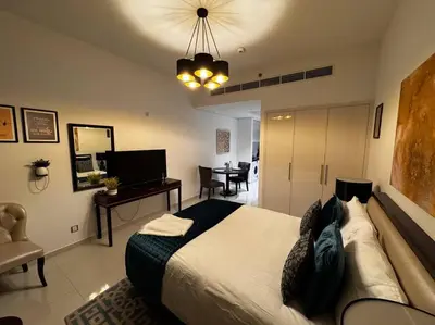 a bedroom with a large bed with a desk and a chair at Ghalia Studio Apartment in Dubai