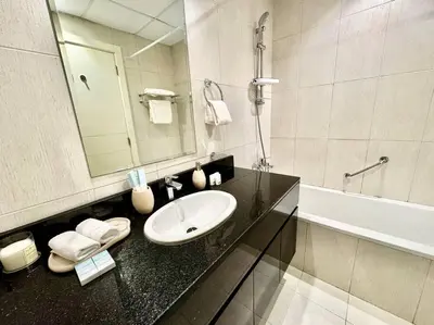 a bathroom with a sink and a mirror and a tub at Ghalia Studio Apartment in Dubai