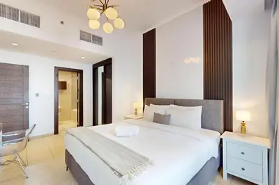 a bedroom with a large white bed and a chair at Silverene Tower B - Exciting Two Bedroom in Dubai