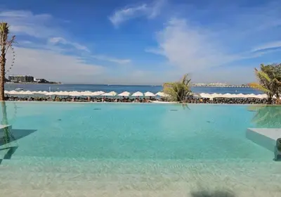 a large swimming pool with a view of the ocean at Luxe 1BD apartment in La Vie with beach access in Dubai