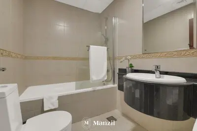a bathroom with a sink and a toilet and a tub at Manzil - 1BR in Elite Residence with Marina View in Dubai