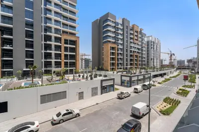 a street with cars parked in a city with tall buildings at Beautiful 1 BR with Gym, Pool & Kid's Playground in Dubai