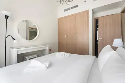 a bedroom with two white beds and a mirror at Beautiful 1 BR with Gym, Pool & Kid's Playground in Dubai