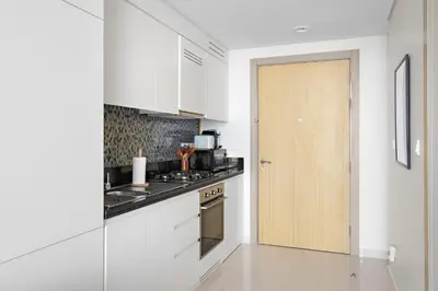 a kitchen with white cabinets and a wooden door at Silkhaus New High Floor Studio In Business Bay in Dubai