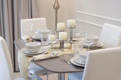 a table with white chairs and a table with wine glasses at Stunning Burj and Fountain View - 2BR in Dubai