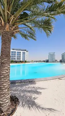 a palm tree sitting next to a swimming pool at Spectacular Lagoon Apartment in Dubai