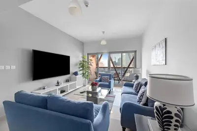 a living room with blue couches and a flat screen tv at First Class 1BR Modern & Stylish Living in Dubai