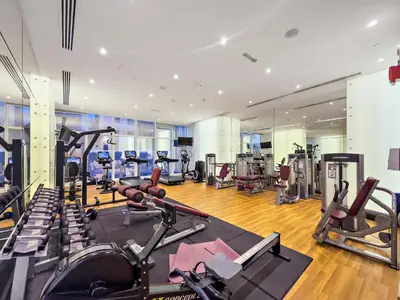 a gym with several treadmills and cardio machines at Dubai 2BR Flat, Marina Views, Pool Access, Parking, Walk to Mall in Dubai