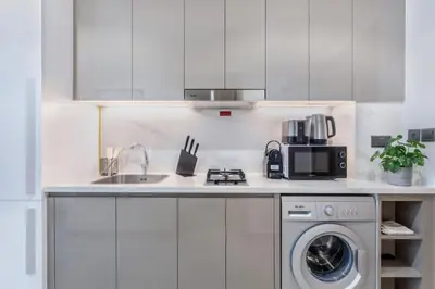 a kitchen with a sink and a washing machine at Lux Stu Bright Urban Escape Stay Near Downtown in Dubai