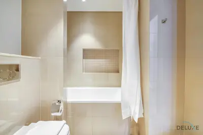 a bathroom with a toilet and a shower with a curtain at Luxurious 2BR Apartment at Boulevard Point Downtown Dubai by Deluxe Holiday Homes in Dubai