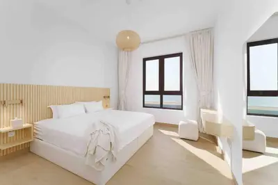 a white bedroom with a large white bed and windows at Beach stylish full sea view in Dubai