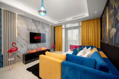 a living room with a blue couch and a tv at Best Burj Khalifa View Balcony Apartment with 64th-Floor Infinity Pool in Paramount Hotel Midtown in Dubai
