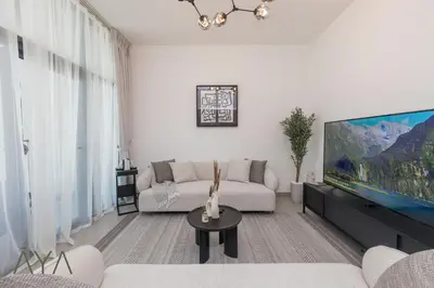 a living room with a couch and a flat screen tv at Stylish 2BR Apartment at Dubai Hills with Pool Access By ĀYA Boutique in Dubai