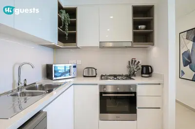 a kitchen with white cabinets and a sink and a stove at HiGuests - Sky-High Luxury 2BR Apt in Downtown Views Dubai in Dubai