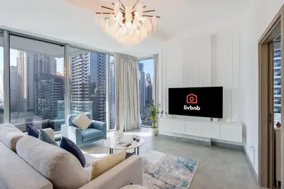 a living room with a couch and a tv at Deluxe 1BR Corner Suite with Marina Views in Dubai
