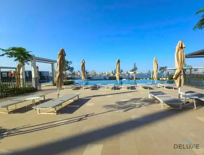 a row of white benches and umbrellas next to the water at Charming 1BR Apartment in Creek Edge Tower 1, Dubai Creek Harbor by Deluxe Holiday Homes in Dubai
