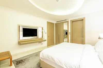 a white bedroom with a bed and a flat screen tv at Dubai Dreaming Stylish 1BR, DAMAC Towers Paramount in Dubai