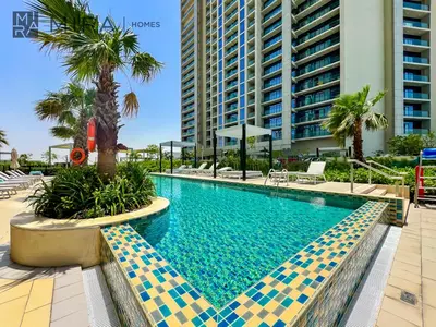 a swimming pool with palm trees and a large building at Mira Holiday Homes - Fully Furnished Studio in Business Bay in Dubai
