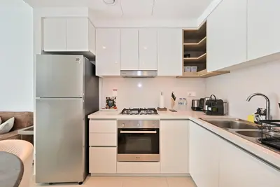a kitchen with white cabinets and a stainless steel refrigerator at Apartment in Downtown Dubai (Burj Khalifa Views) in Dubai