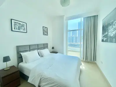 a white bedroom with a large bed and a window at JBR Walk Full Apartment Marina View in Dubai