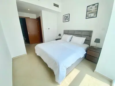 a white bedroom with a large white bed with white sheets at JBR Walk Full Apartment Marina View in Dubai