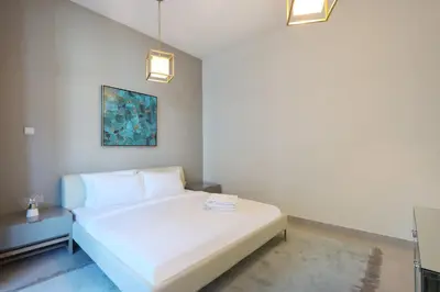 a bedroom with a white bed and a painting at 2BR in Central Marina Walk to Dining & Nightlife in Dubai