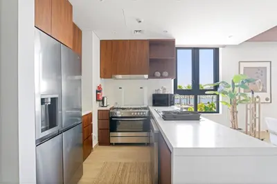 a kitchen with wooden cabinets and a white counter top at Ocean View 2BR with a Pool & Gym, 2 min to Beach in Dubai