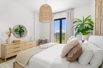 a white bedroom with a large bed and a mirror at Ocean View 2BR with a Pool & Gym, 2 min to Beach in Dubai